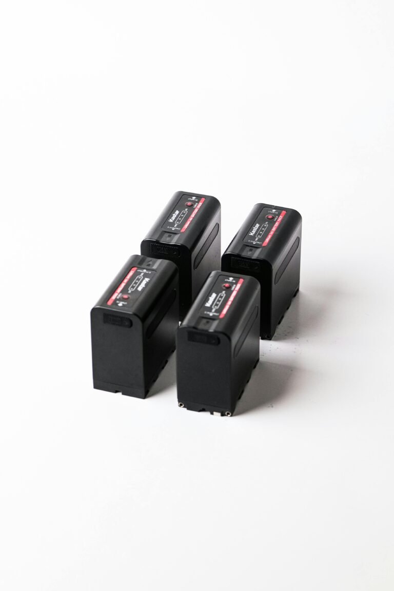 Four rechargeable camera batteries standing upright arranged in a square formation on a plain white background.